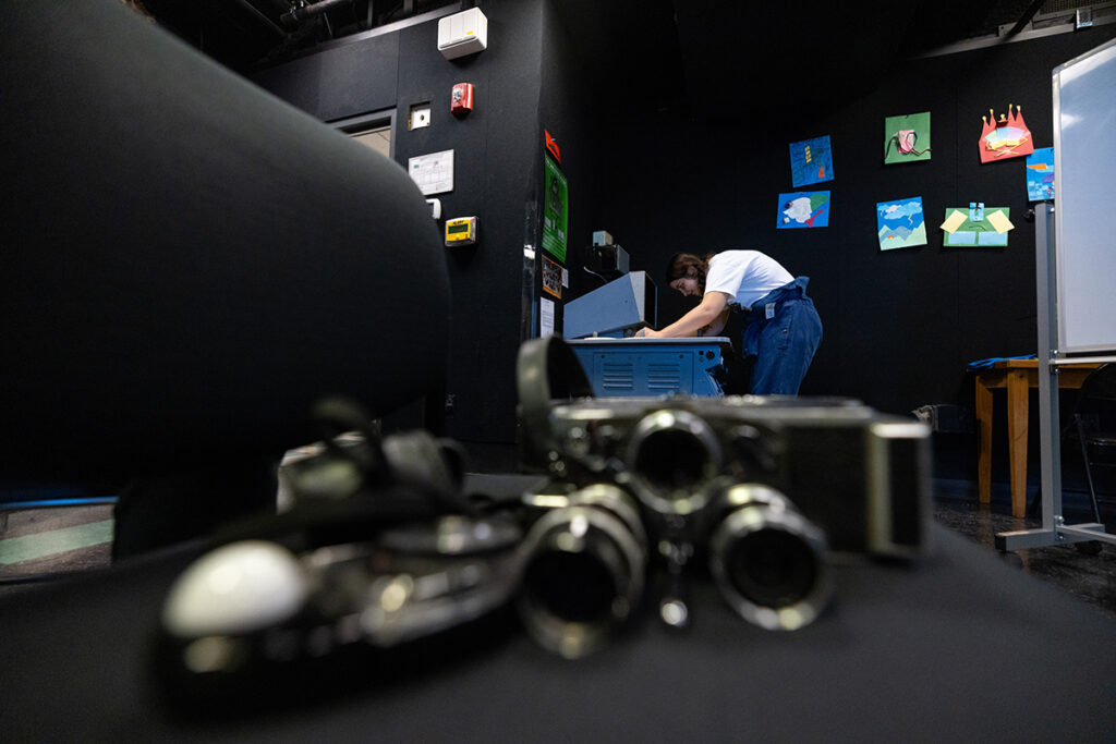 Student works at light table as analog film equipment sits on a table in the foreground