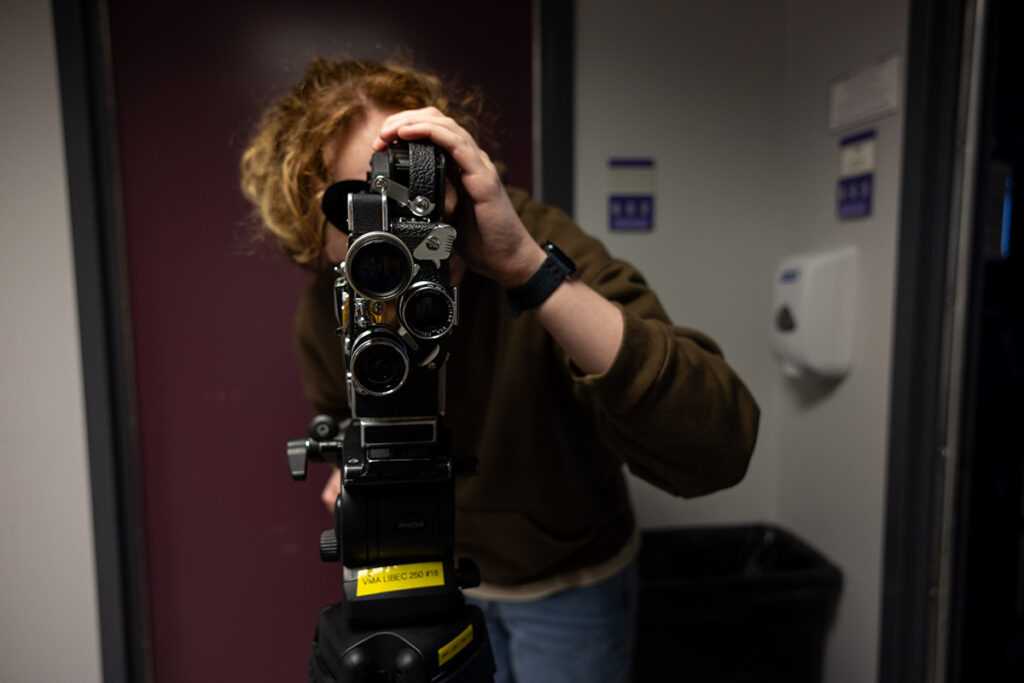 student looks through 16mm film camera