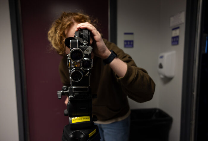 student looks through 16mm film camera