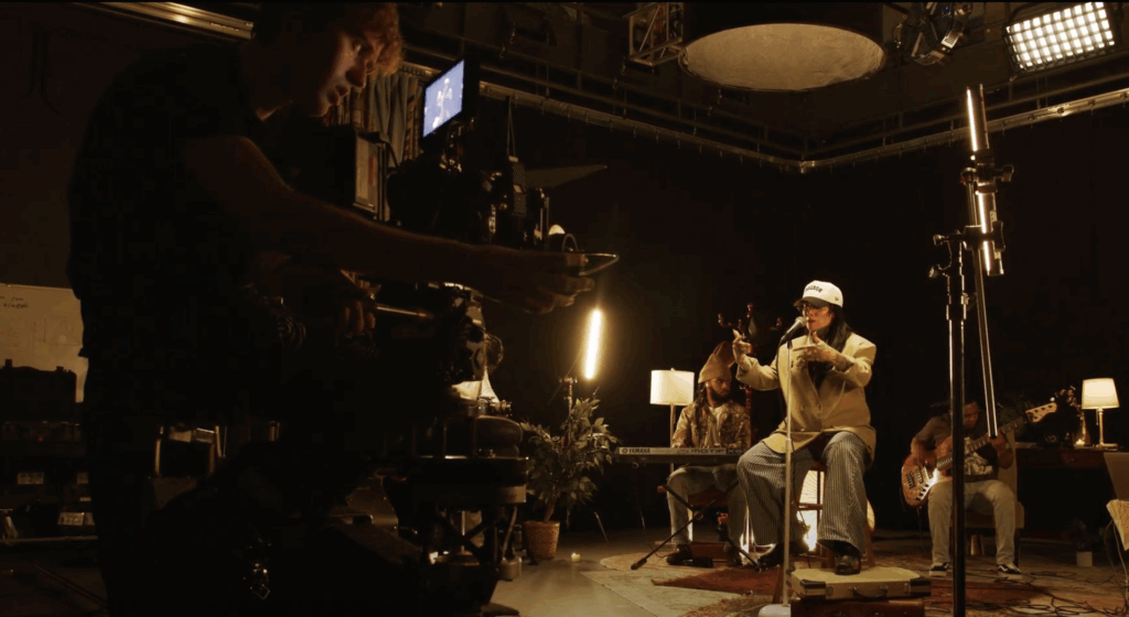 Sebastian Anderson operates a camera on a dolly recording Lisa Bello and her band perform