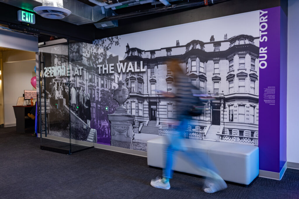 A blurred person walks by a wall