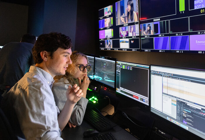 Two students in a control room, looking at a monitor