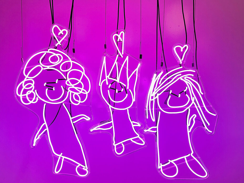 Neon outlines of a queer family suspended from wire in front of a purple background