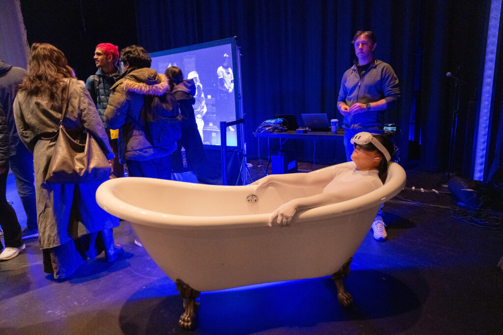 A person lays in a bath tub with a VR headset on