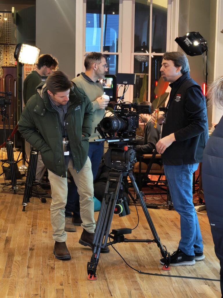 Thomas Brady looks at a filmmaker's camera on a tripod