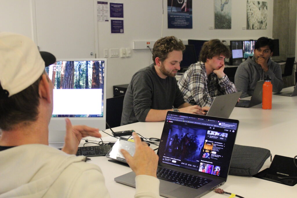 Students with laptops sit around a table
