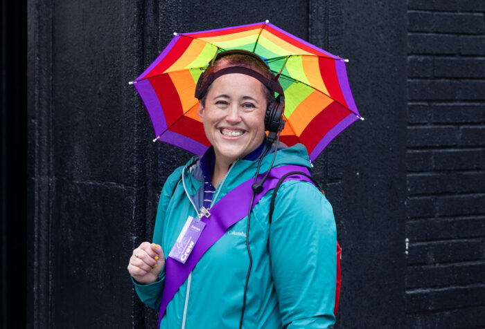 Kellie Fuller in blue jacked, rainbow umbrella hat