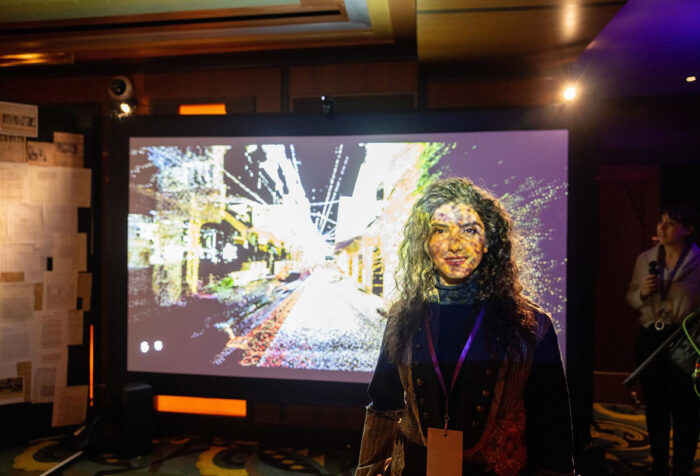 Asma Khoshmehr stands in front of a screen of her installation