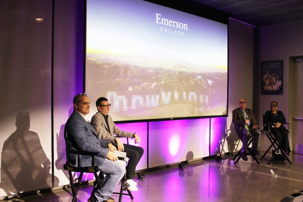 Four panelists sit in chairs with a screen behind them. The screen shows a photo of the Hollywood sign projected onto it.