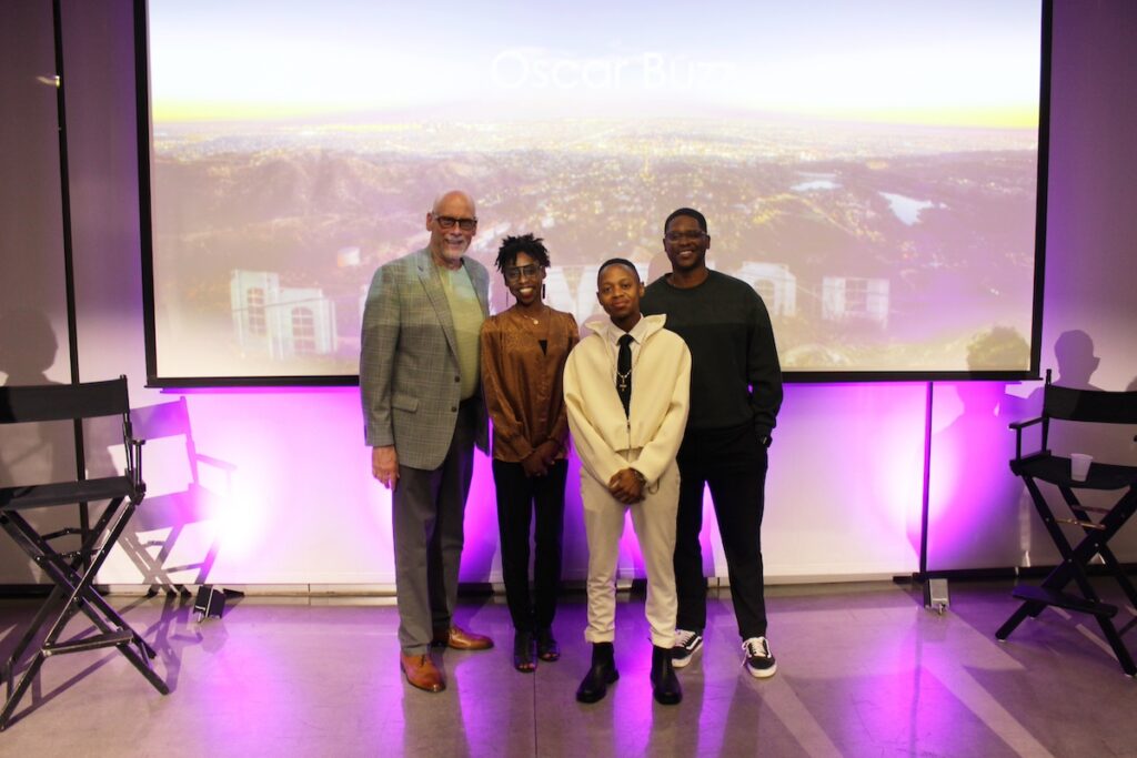 Photo of Ken Grout, Sharifa Simon-Roberts, Ikanyeng Rammutla, and Rey Saint-Vil standing in front of a screen