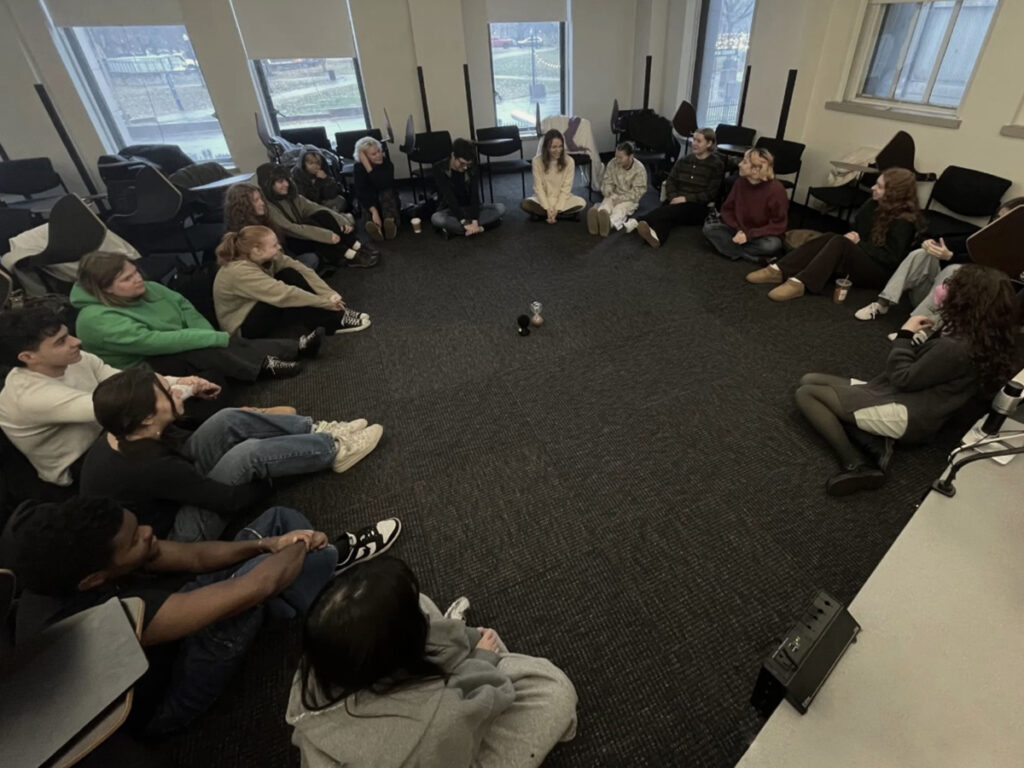 Students sit on the floor in a circle