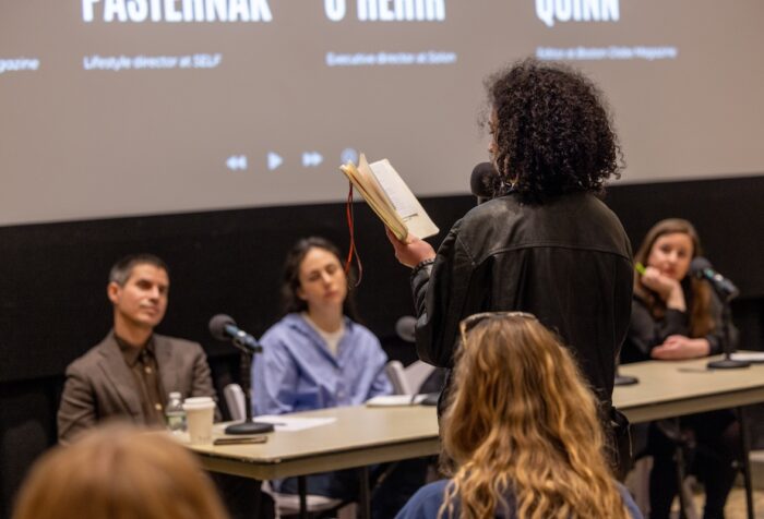 Student with their back to the camera, faces a panel of journalists to pitch their story idea