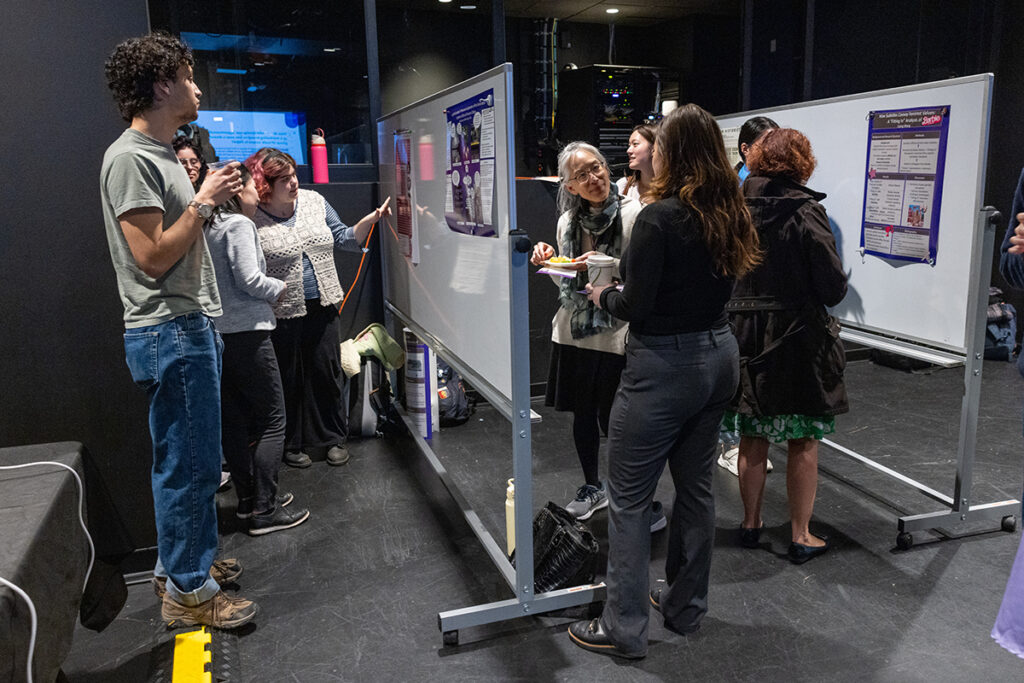 people mingle, look at posters taped to white boards