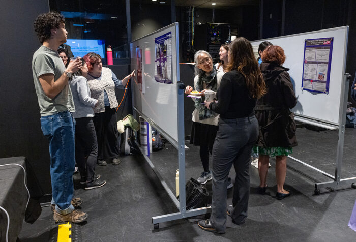 people mingle, look at posters taped to white boards