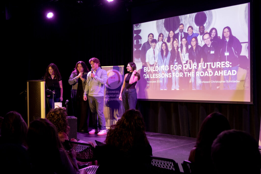 Four people stand on stage presenting about their project