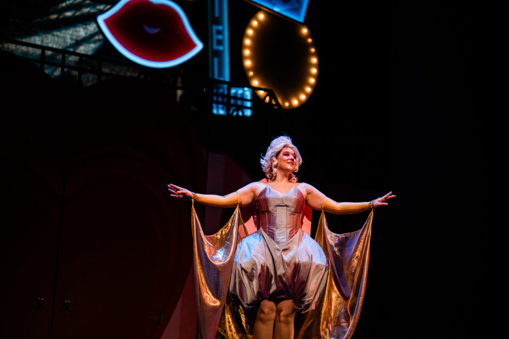 Emily Barnett dressed as the Good Fairy. The dress is elaborate with big poofs and clothing draped from her arms