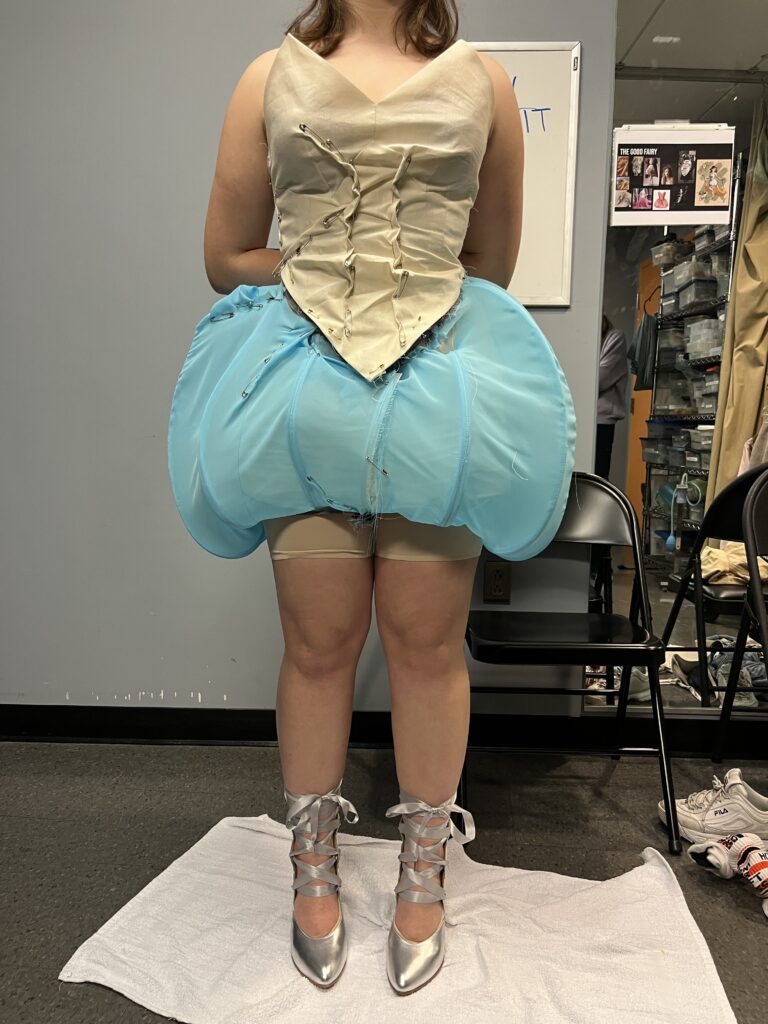 The lower half of the dress is seen from a person's chest down