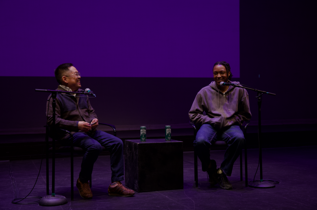 Ed Le and Josh Johnson sit on chairs on a stage and talk
