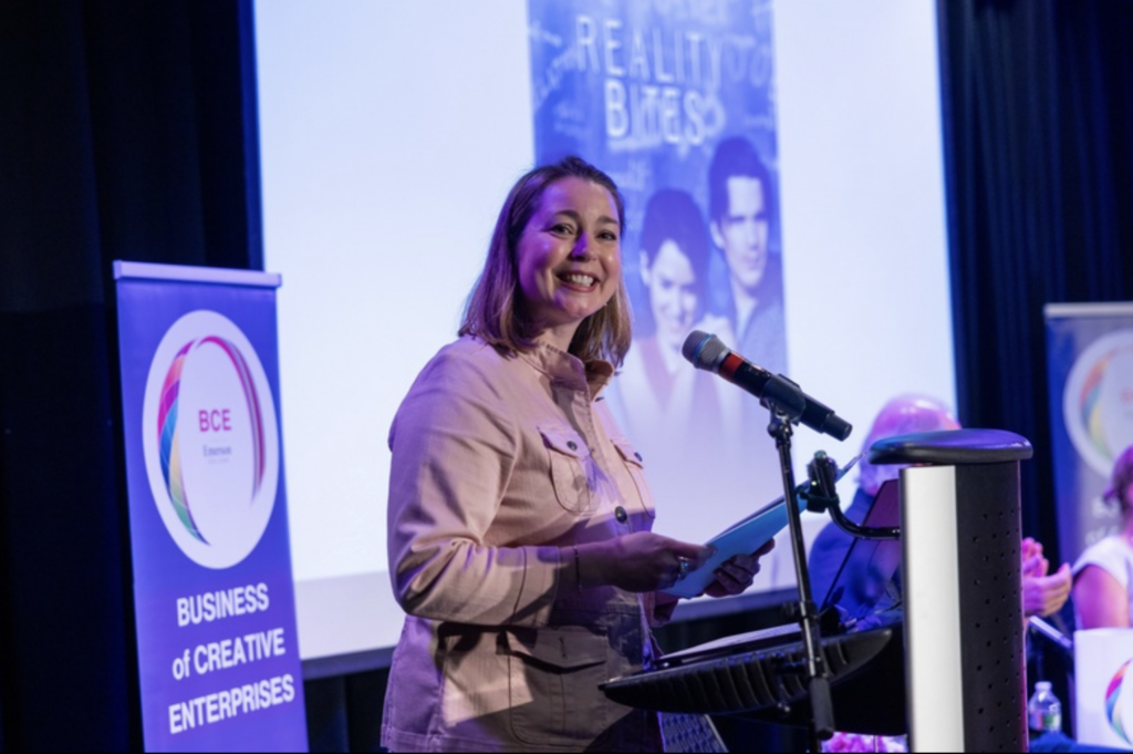 Brenna McCormick stands in front of a microphone while smiling
