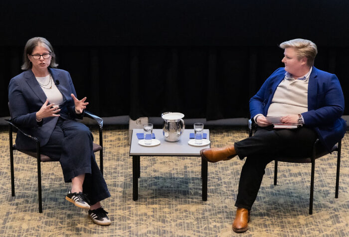 Jane McManus sits in a chair while speaking with Mary Ann Taylor, who is also sitting