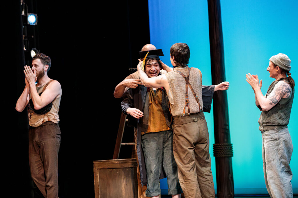 Nicholas Papayoanou reacts with surprise as he receives his Emerson College diploma during the curtain call for Swept Away.