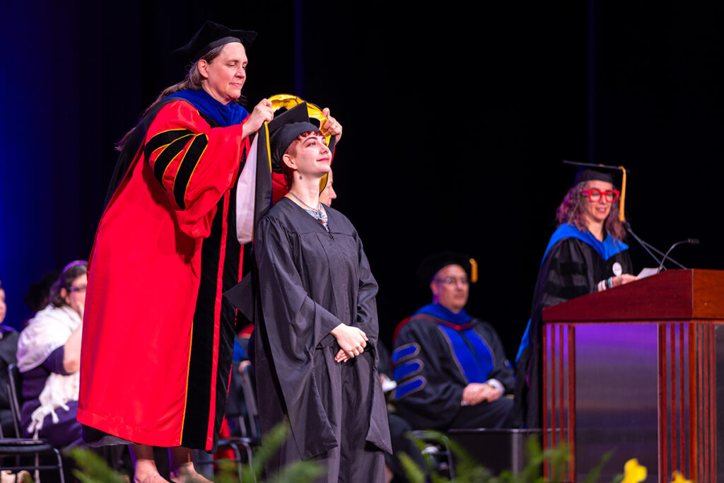 Provost places hood over graduate's head