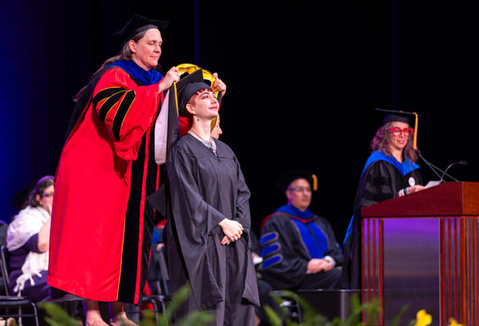 Provost places hood over graduate's head