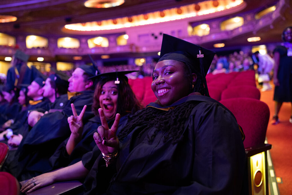 Graduates give peace sign from seats at Wang