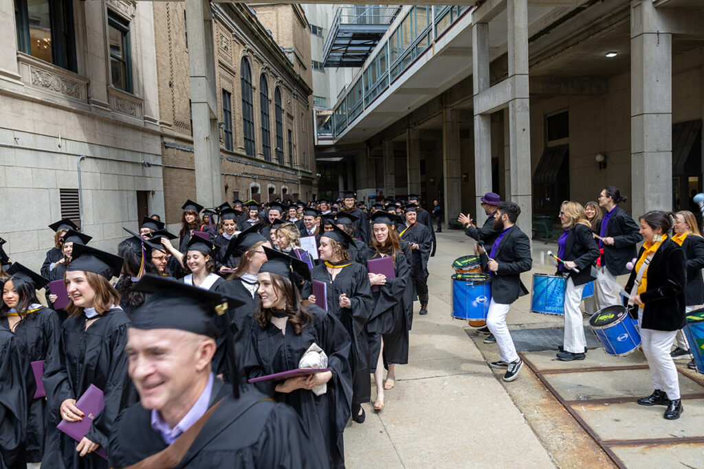 Graduates process outside Wang Theatre as Grooversity plays