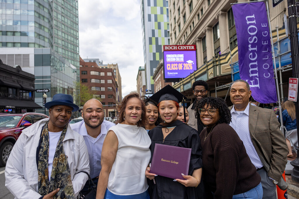 graduate holds diploma surrounded by family