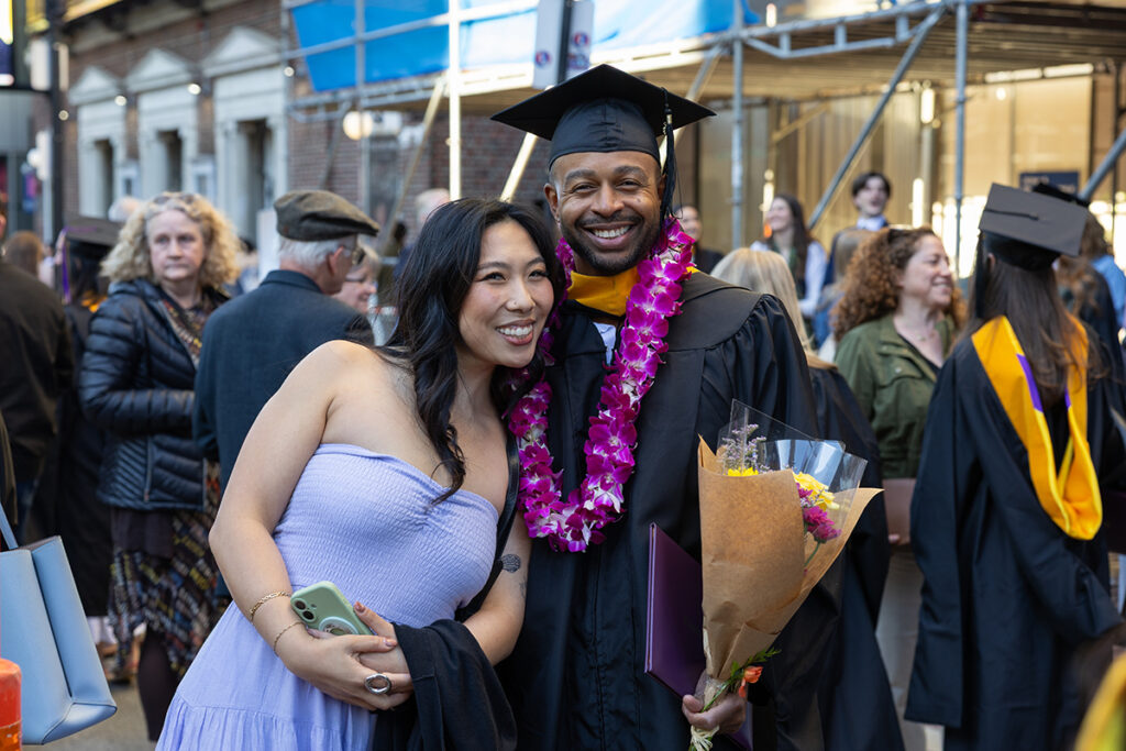 Graduate wearing purple lei poses with friend