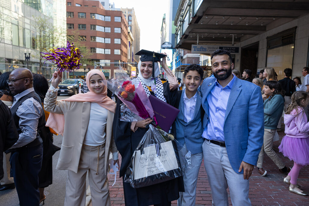 Graduate holding diploma, flowers is surrounded by family
