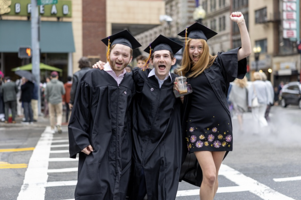 Three graduates cross the street boisterously