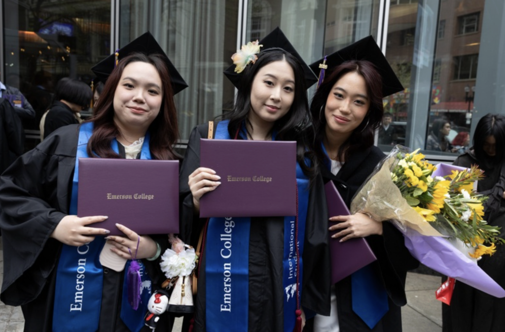 Three people pose for a photo with their diplomas