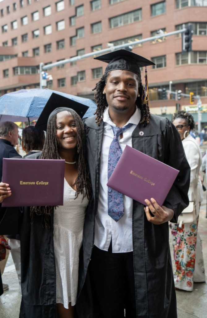 Two people pose for a photo with their diplomas