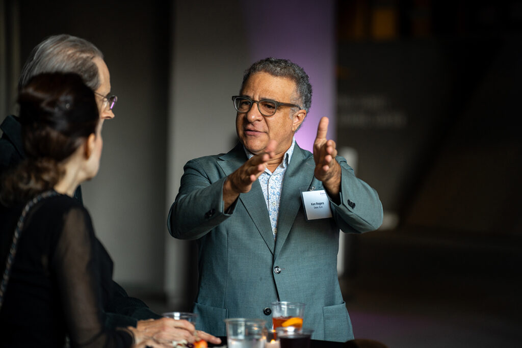 Man in suit gestures as two other people look on